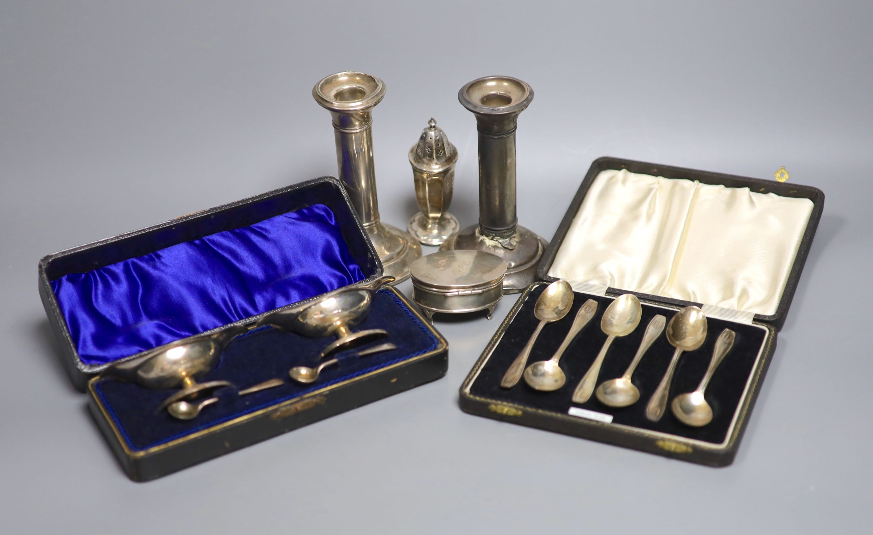 A pair of silver dwarf candlesticks(a,7.f.), 13cm, a small silver trinket box, a silver pepperette and two cased silver sets including a pair of salts and set of six teaspoons.